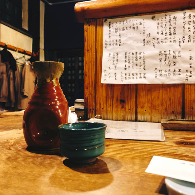 A cup and a small bottle of sake in a small izakaya in the center of Kyoto, Japan.
