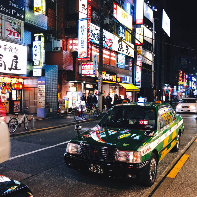 A taxi waiting near Ryogoku Station, lit by the restaurant signs in the street at night in Tokyo, Japan.