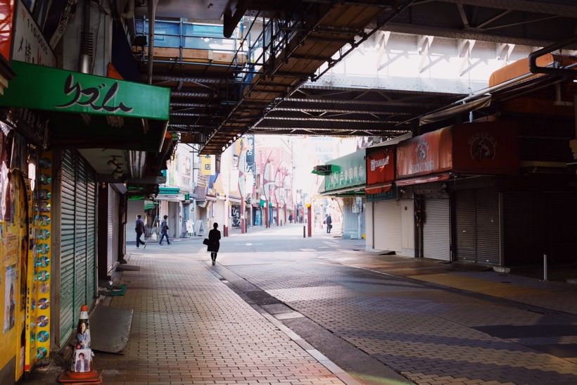 A clean, near empty street underneath a metro line with closed shops in Ueno, Japan.
