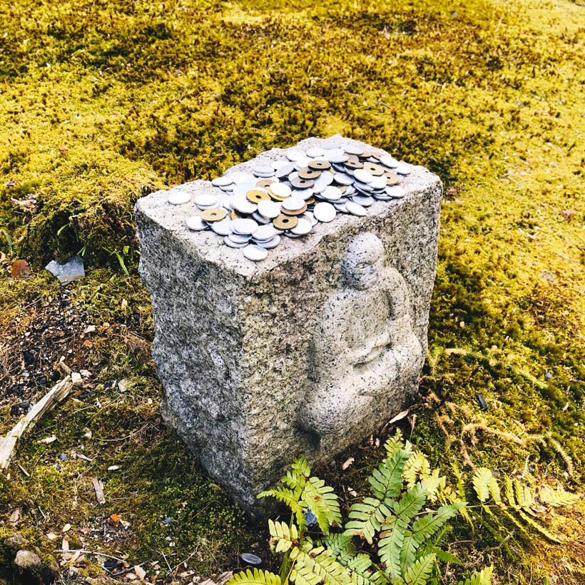 Coins offered on a Buddhist statue at Adashino Nenbutsu-ju temple in Kyoto, Japan.