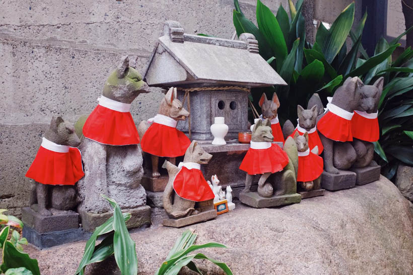 Fox statues with red yodarekake around their necks at the Namiyoke Inari Shrine near Tsukiji Fish Market in Tokyo, Japan.